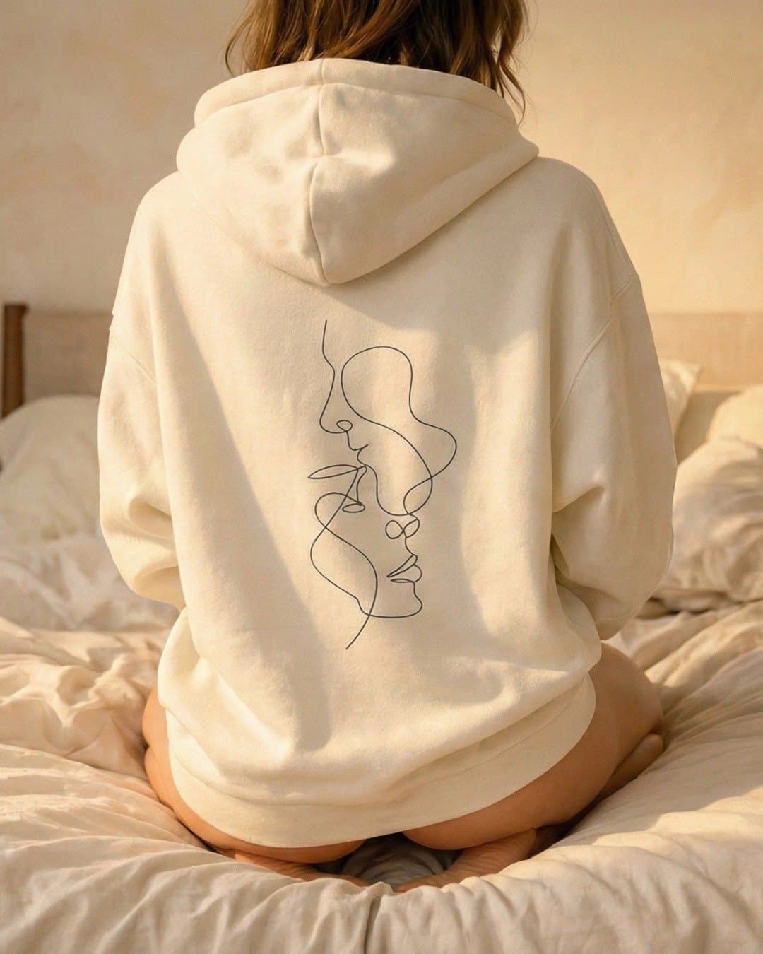 The back of a cream hoodie with a one-line portrait.